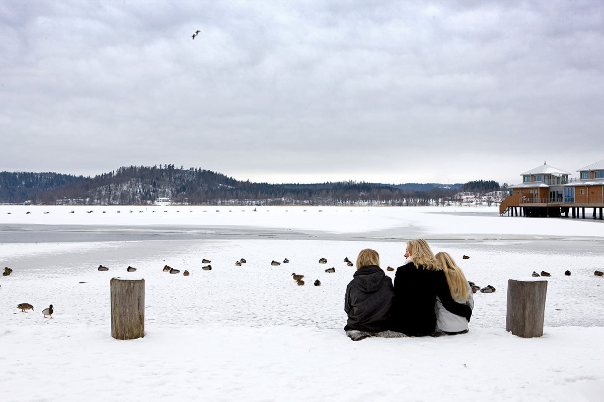 Tre personer sitter och tittar ut över Åsunden
