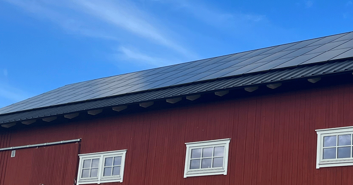 solceller monterade på ett svart ladugårdstak