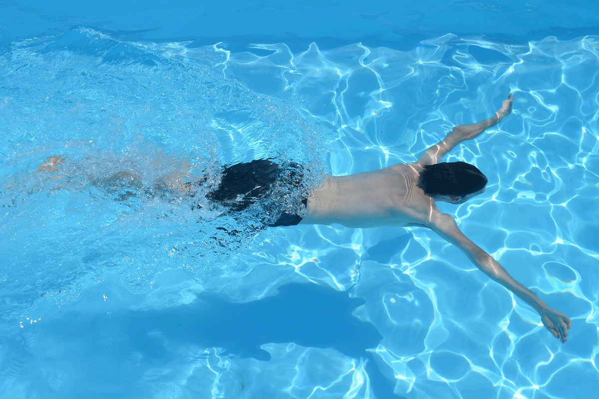 En kille simmar under vattnet i en pool