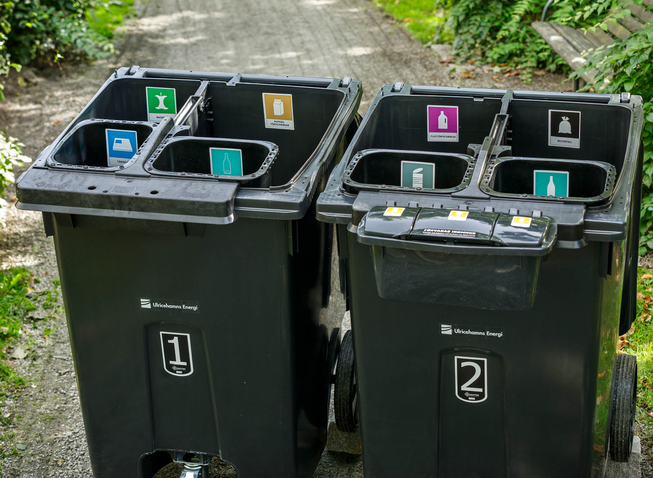 Två fyrfackskärl uppifrån med öppna lock, visar indelning och dekaler