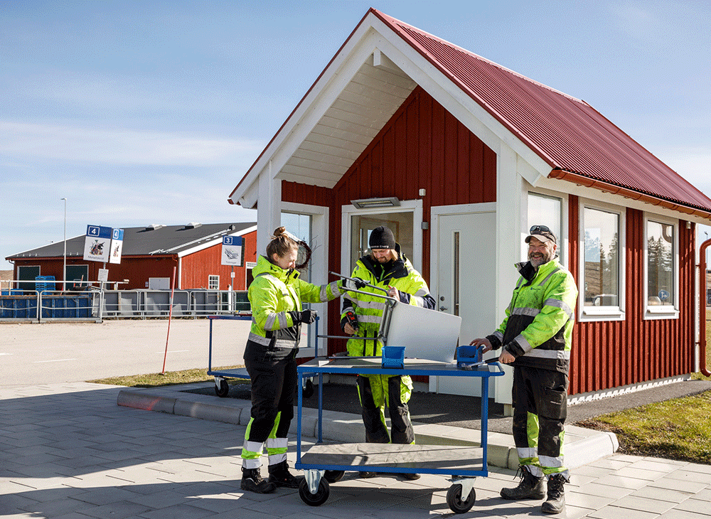 Tre personer i varselkläder monterar av stolsben i metall ifrån en trästol.