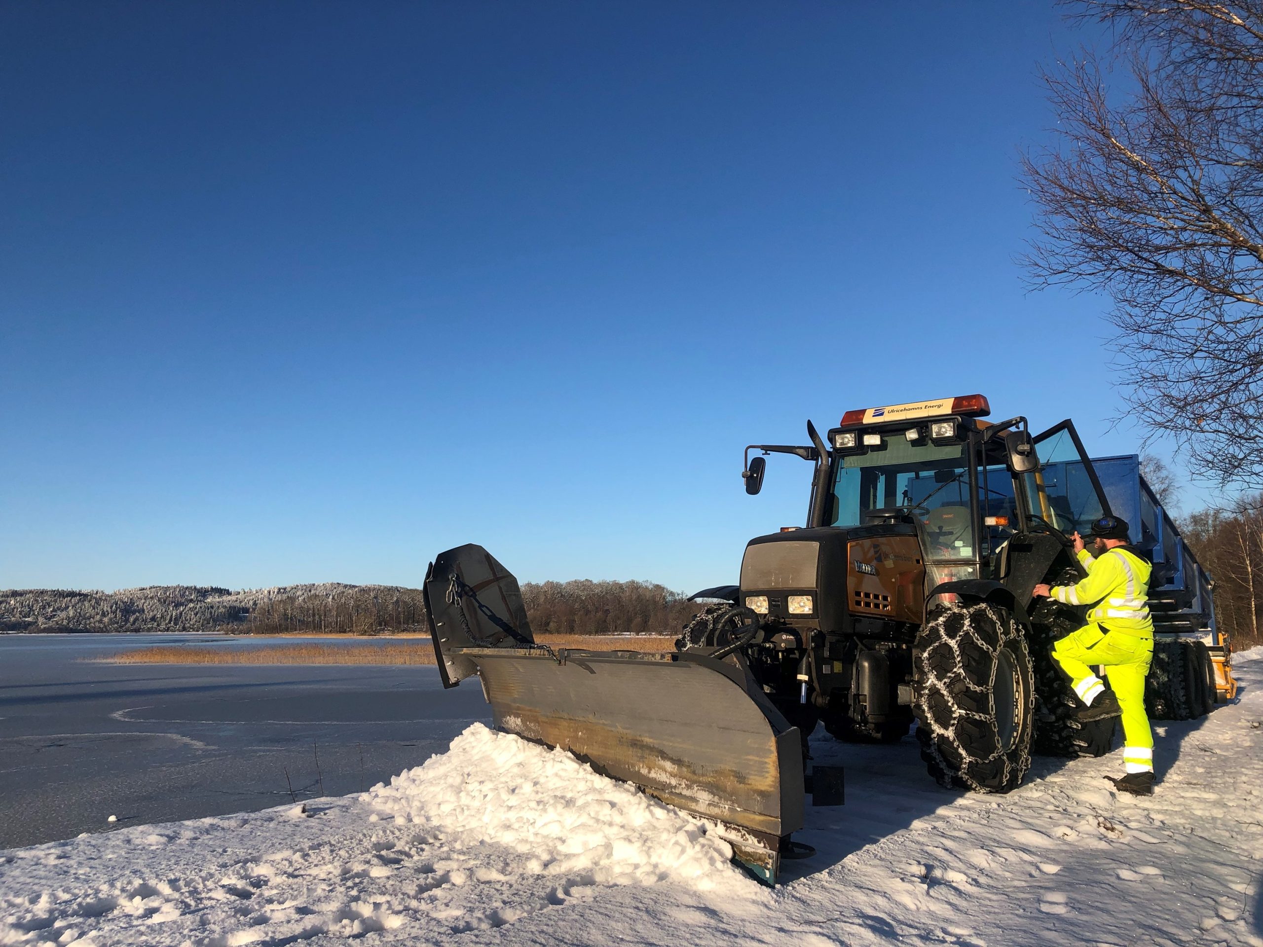 Traktor med plogblad plogar snö