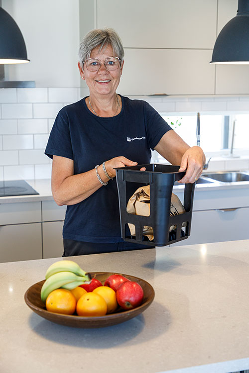 7_papperspase Kvinna bär den fulla papperspåsen för matavfall i matavfallskorgen, som har handtag.