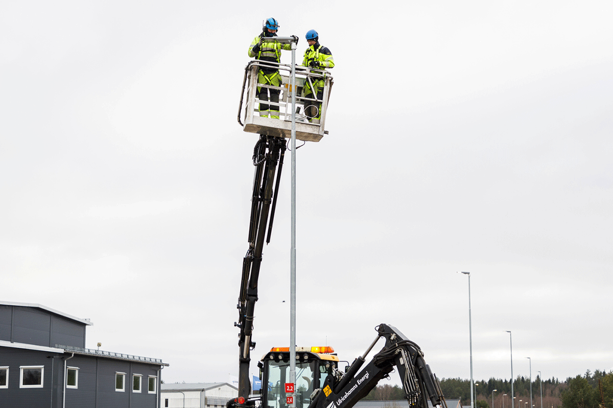 Två installatörer i varselkläder byter en gatljusarmatur