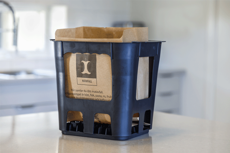 En svart korg med en papperspåse inuti.