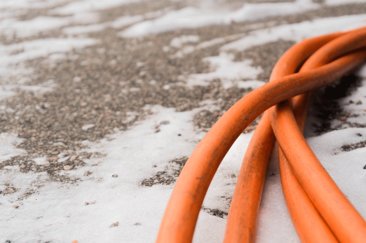 Fyra orange sladdar ligger på marken med ett lätt snötäcke.